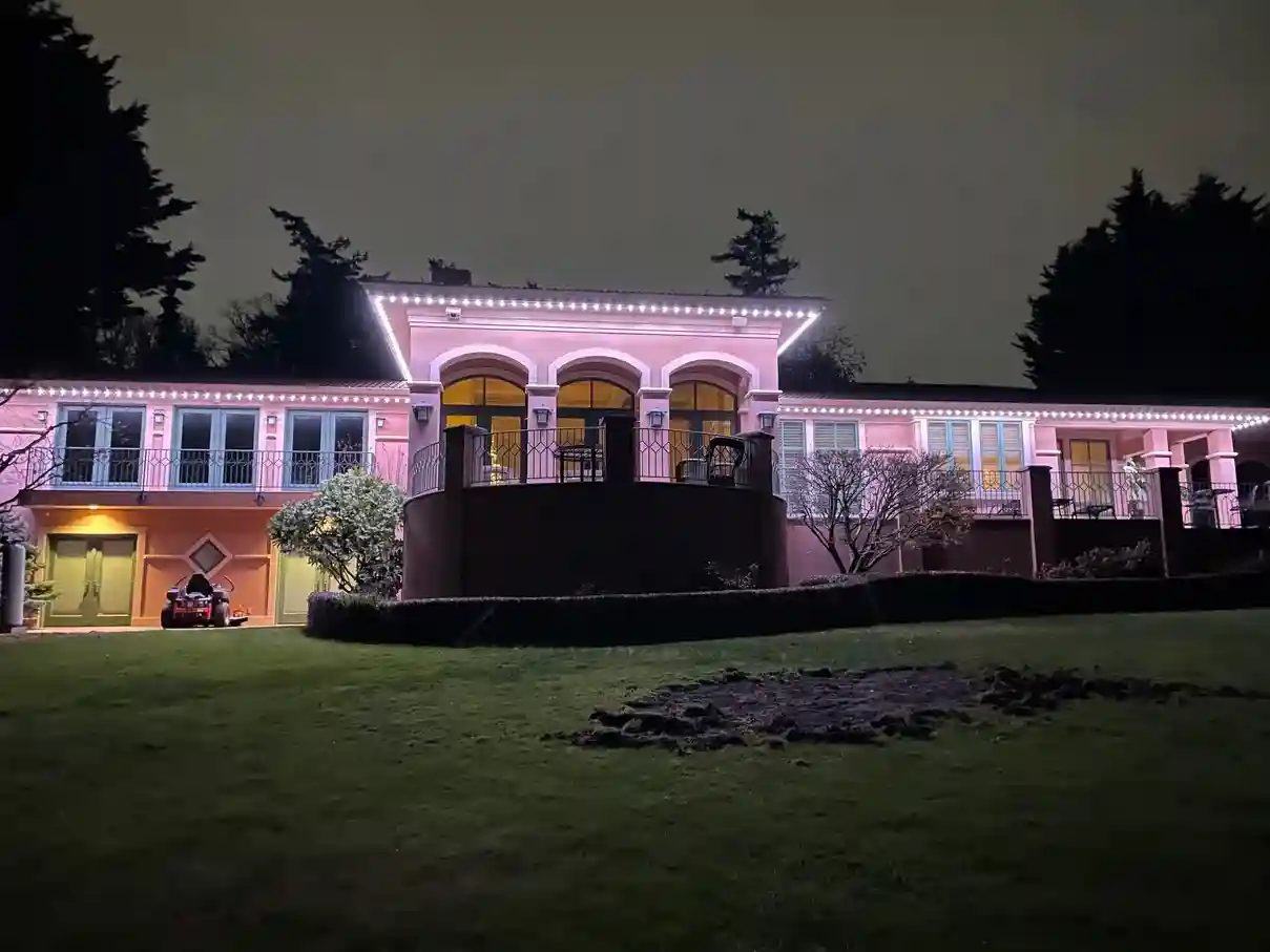 Pink permanent lighting across a large home's rooflines